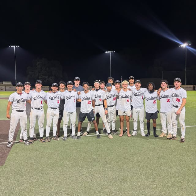 Cal State Peloteros players together on the field under the stadium lights